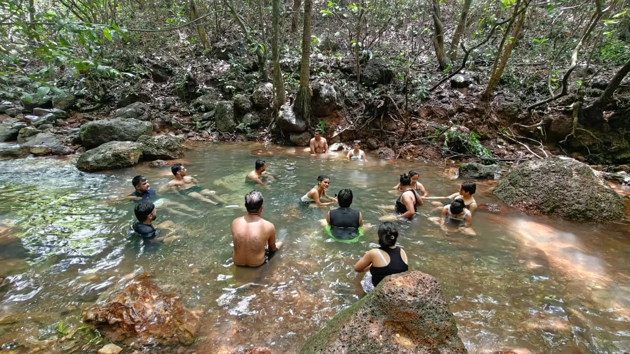 Travellers soaking in a hidden forest stream on a Goa Unseen trip
